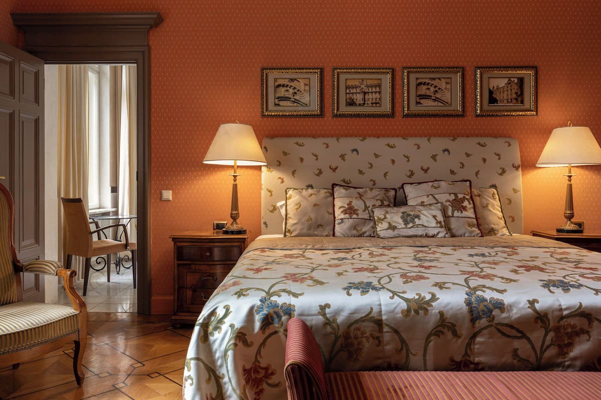 A hotel room with a large bed, two bedside tables with lamps, a chair, and a desk with a chair.