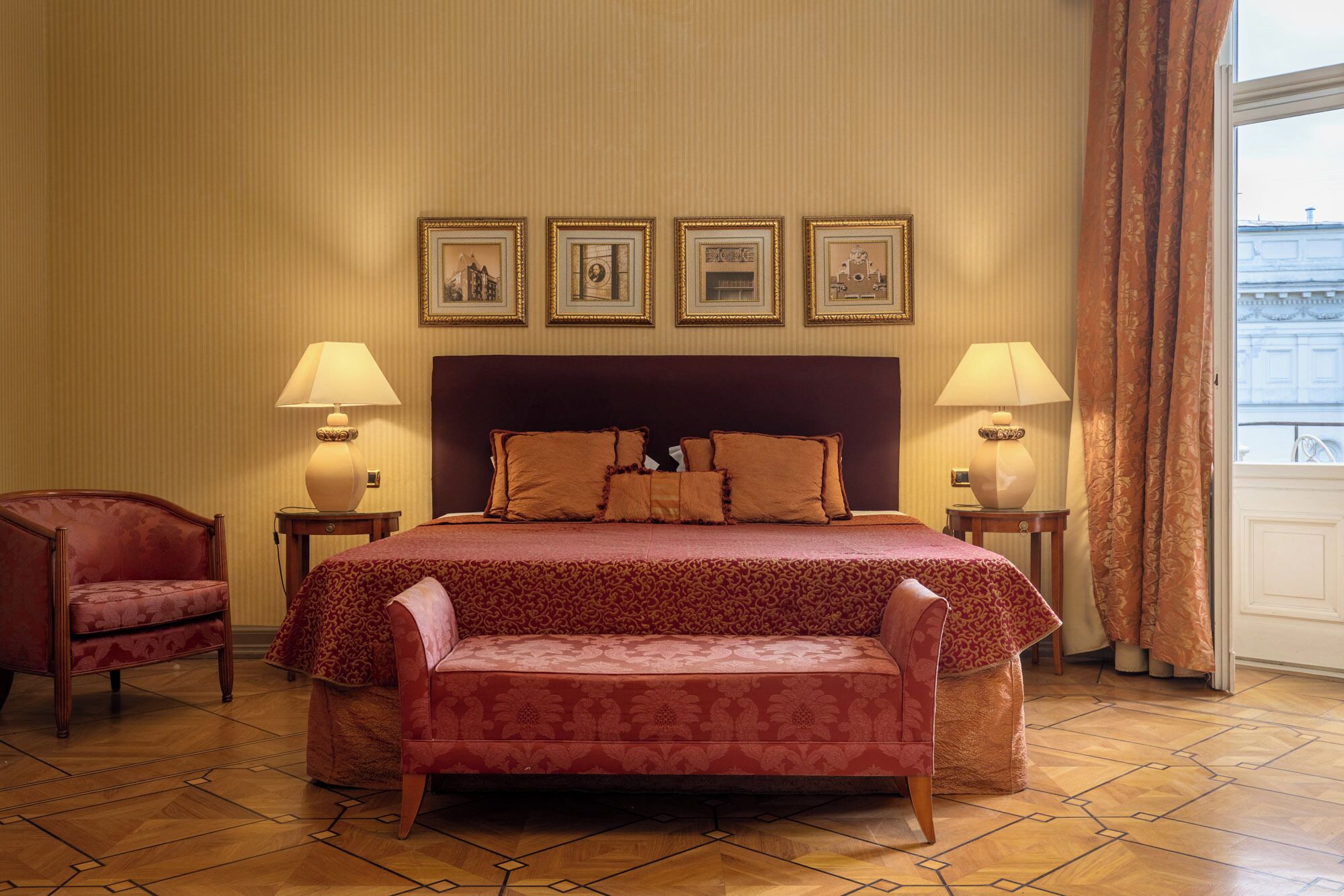 Une chambre d’hôtel avec un grand lit, deux lampes de chevet, un fauteuil et une vue sur la ville.