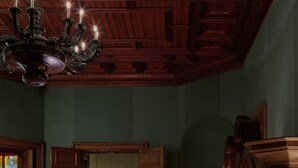 Une pièce chaleureuse avec un plafond en bois, un lustre, un fauteuil rose, un banc et un tapis à motifs.