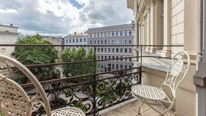 Un balcon doté de balustrades en fer forgé et de deux chaises blanches.