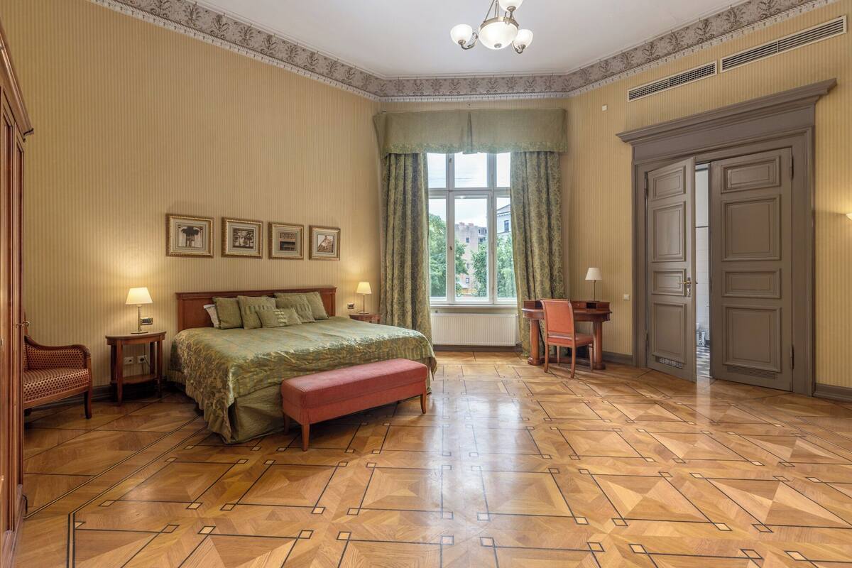 A hotel room with a large bed, a desk, a chair, a wardrobe, and a window with curtains.