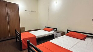 A room with two single beds, a wardrobe, a ceiling fan, and a wall-mounted coat rack. - Professional Lahore Hostels (Lahore)