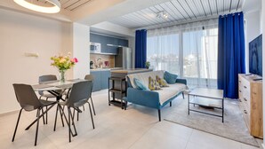 Un apartamento moderno con comedor, sofá, mesa de centro y cocina al fondo.