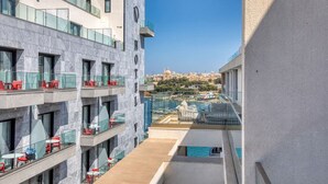 Un hotel moderno con varios balcones, mobiliario exterior y vistas a un paisaje urbano histórico.