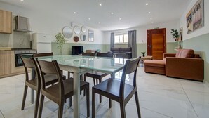 A modern kitchen with a dining area, a living room with a sofa, and a TV. - An amazing 3BR maisonette with private terrace &AC (Marsaskala)