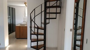 Un interior moderno con una escalera espiral que conduce a una zona de cocina.