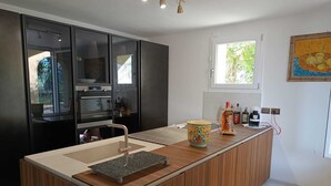 Una cocina moderna con armarios oscuros, una isla de madera y un ventanal que proporciona luz natural.