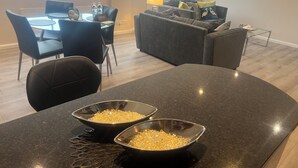 Un salon moderne avec un coin repas, comprenant une table sur laquelle sont disposés des bols remplis de collations, un canapé et une lampe.