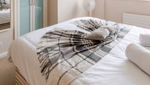 Une chambre à coucher avec un lit, une lampe de chevet, une fenêtre et une armoire.