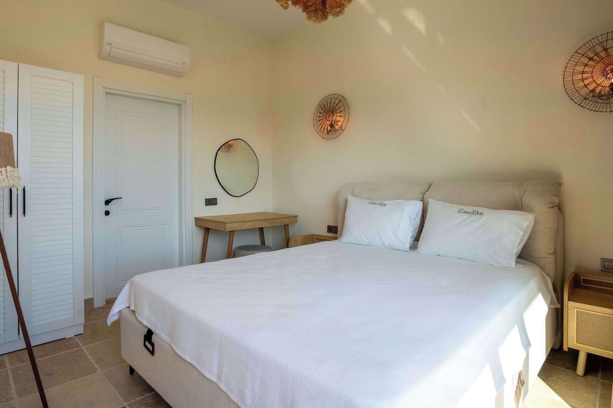 A bedroom with a bed, a desk, a chair, a lamp, and a wardrobe.