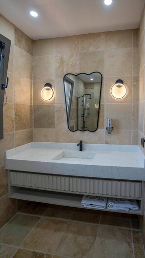 A bathroom with a large sink, two wall-mounted lights, a mirror, and a towel rack with towels labeled "Casa Mies."