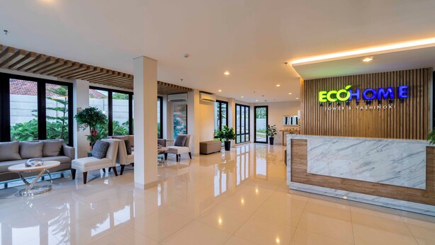 Un hall d’hôtel moderne avec un comptoir d’accueil, un espace salon et de grandes fenêtres.