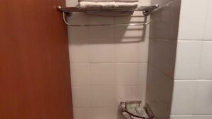 Une petite salle de bain comprenant des toilettes, un porte-serviettes et un savonnetier.