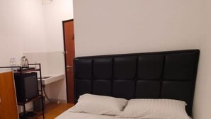 Une chambre à coucher avec un lit, une petite table de chevet, un téléviseur et une porte.