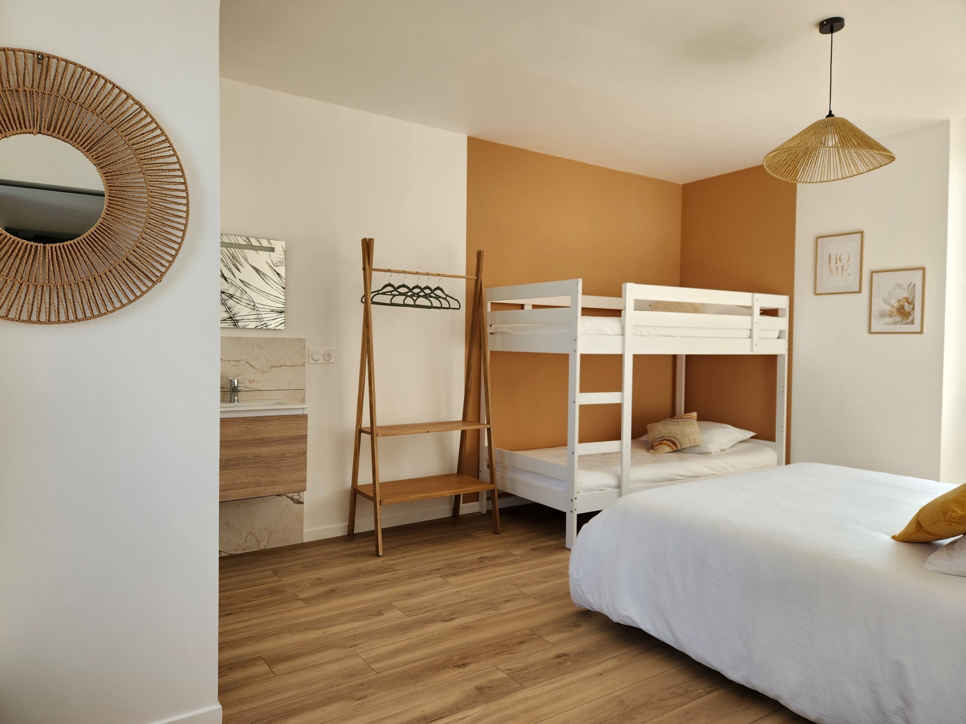 A bunk bed room with a wooden ladder, a hanging rack, a round mirror, and a pendant light.