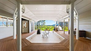 A covered patio with a view of a green landscape, a table with chairs, and a barbecue grill. - 58 Mystery Bay Road, Mystery Bay (Central Tilba)