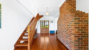 A staircase with wooden balusters leading to a door with a view of greenery outside.
