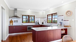 A spacious kitchen with a large island, wooden cabinets, and a view of the outdoors through the windows.