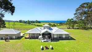A large, two-story house with a covered patio and a view of the ocean.