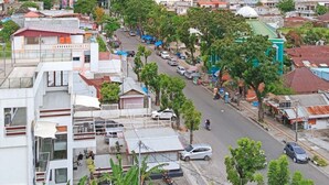 A cityscape with a mix of modern and traditional buildings, a wide street, and a view of the ocean. - Hotel My All Padang (Padang)