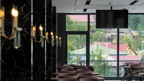 Een modern restaurant met een lange eethoek, marmeren wanden en een groot raam met uitzicht op de stad.