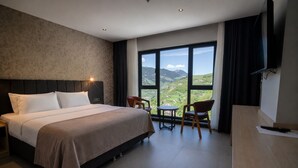 Een hotelkamer met een groot bed, een bureau, een stoel en een televisie.