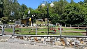 Un parque infantil con columpios y un pequeño refugio.
