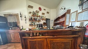 Una zona de bar con armarios de madera, estantes con botellas y una máquina de café.