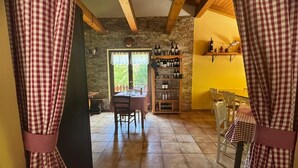 Un comedor rústico con mantel a cuadros, vigas de madera y pared de piedra.