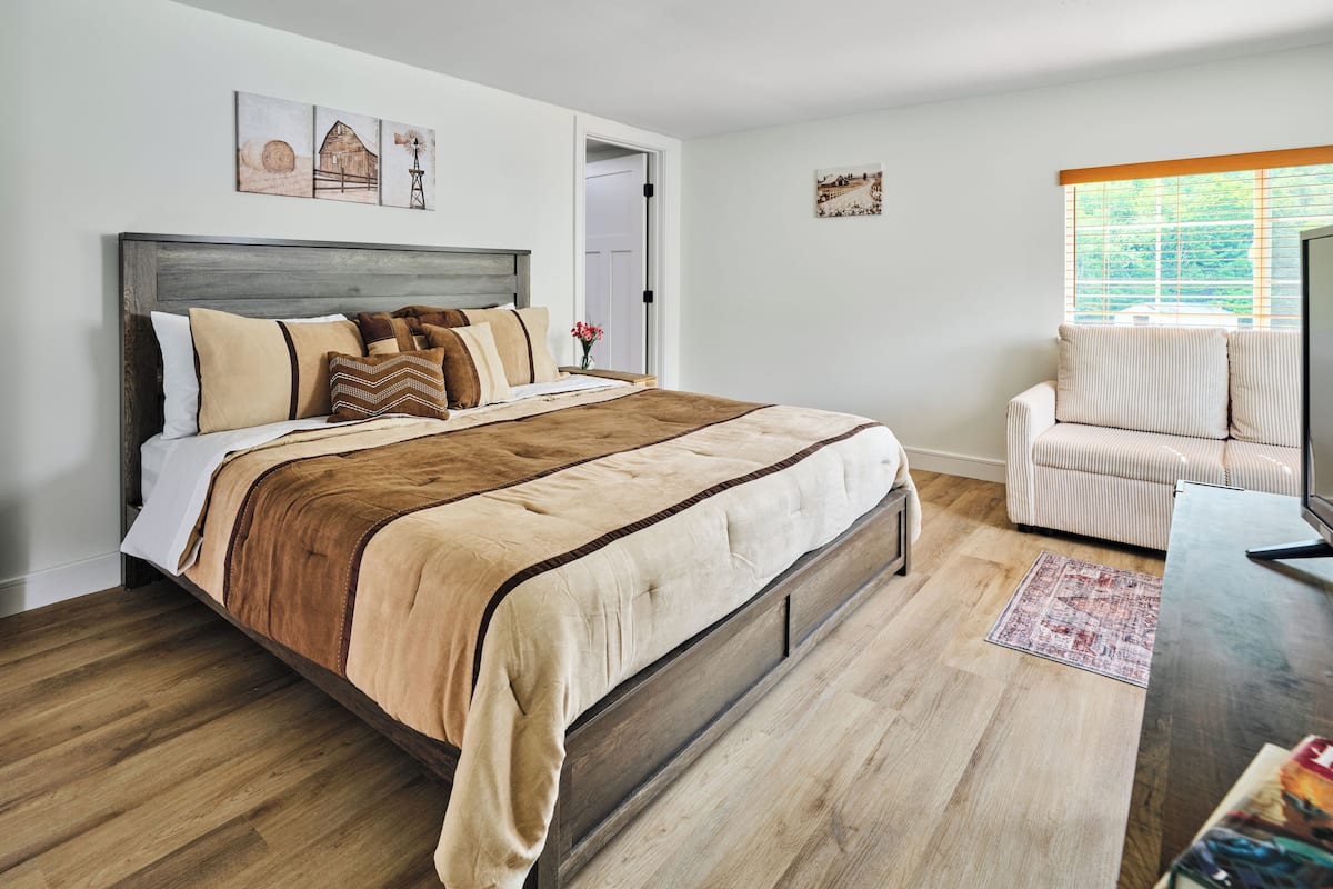 Un dormitorio con cama de madera, una silla y obras de arte en las paredes.