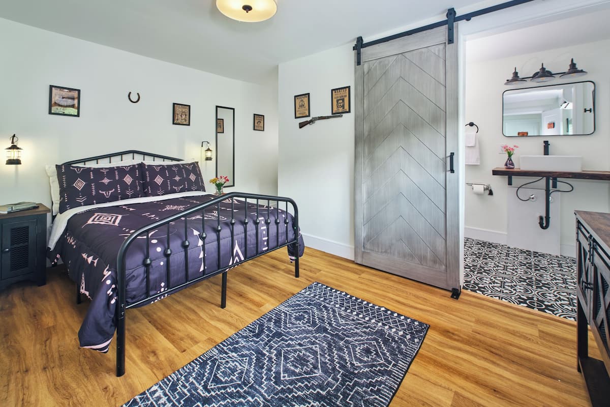 Un dormitorio con cama, cómoda, espejo y puerta corredera.