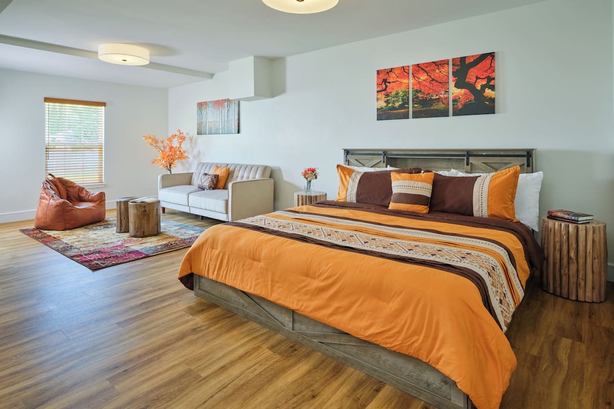 Un dormitorio moderno con una cama grande, un sofá y un sillón orejero.