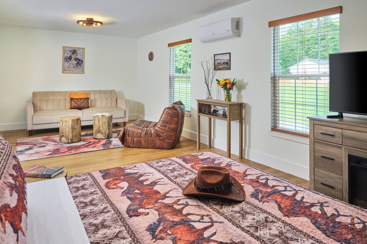 Una sala de estar con sofá, sillón de cuero, mesa de centro, televisor y chimenea.