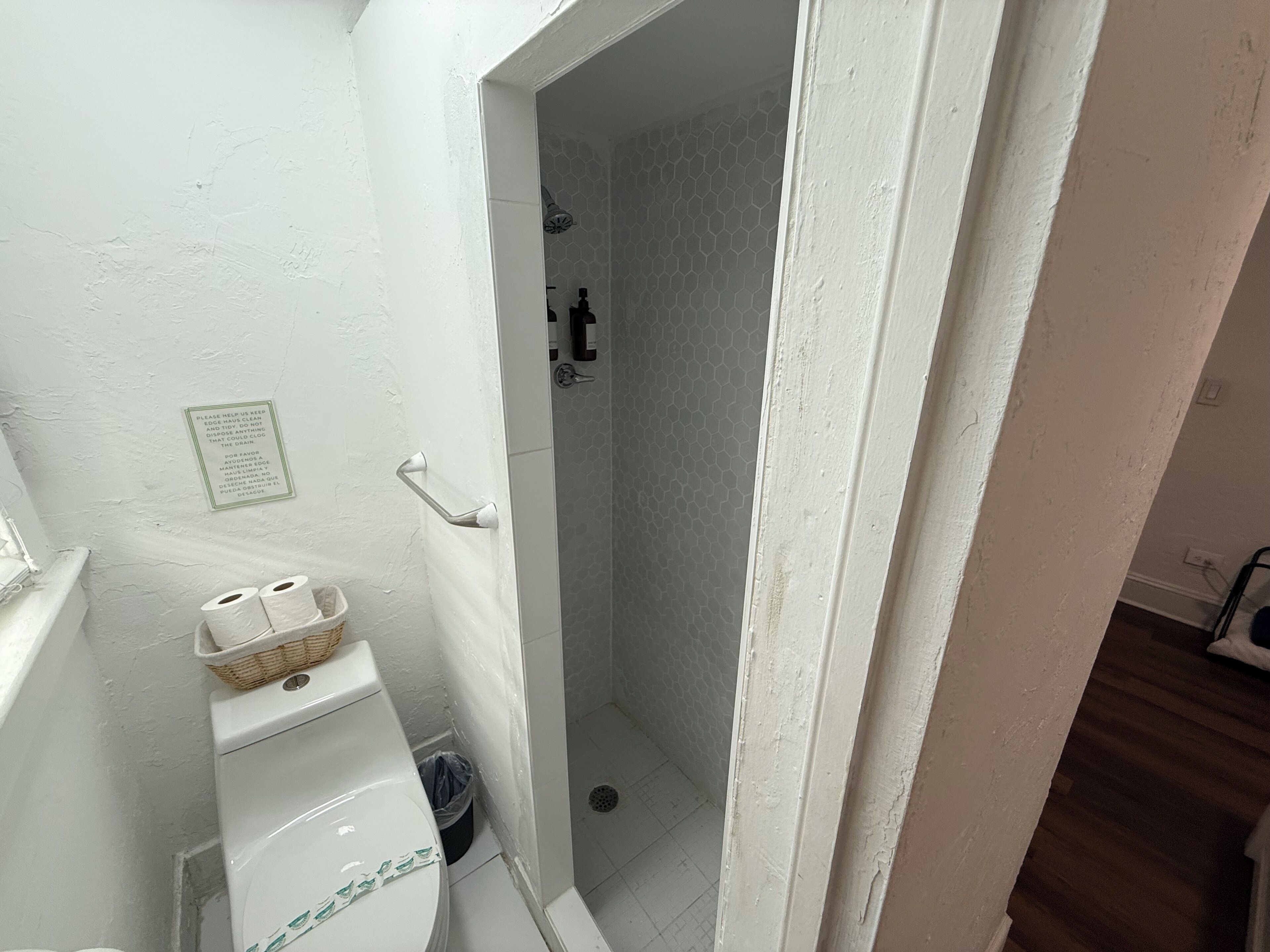 Une petite salle de bain avec des toilettes, une douche et une porte blanche.
