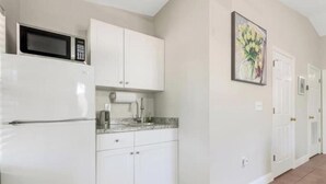 A kitchen with white cabinets, a microwave, and a sink.