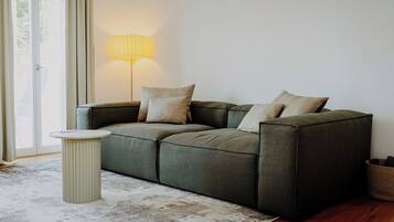 Ein modernes Wohnzimmer mit einem Ecksofa, einem runden Beistelltisch und einer Stehlampe.