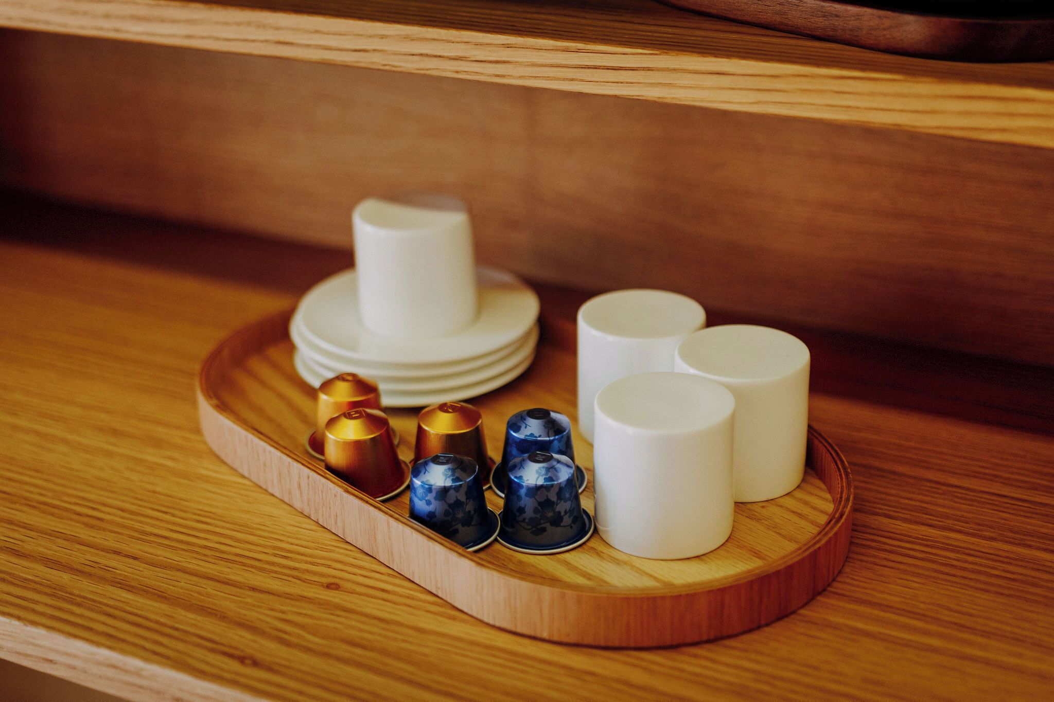 A wooden tray with various cups and saucers on a shelf.