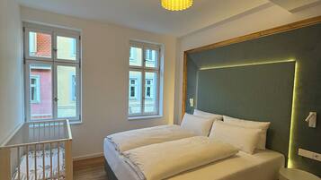 Een slaapkamer met een groot bed, een ledikant en uitzicht op een gebouw door de ramen.