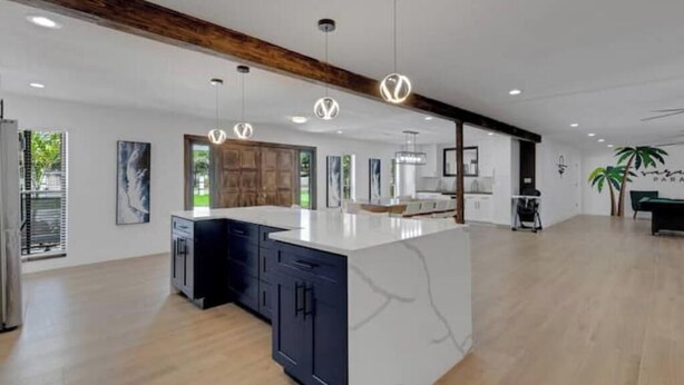 A modern kitchen with a marble island, dark cabinetry, and pendant lighting. - Sarasota Paradise Special Events (Sarasota)