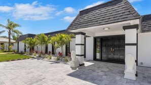 A modern house with a tiled driveway, palm trees, and a statue. - Sarasota Paradise Special Events (Sarasota)