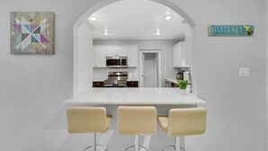 A modern kitchen with white cabinets, a white countertop, and three bar stools. - Sunseeker Paradise for 8! (Port Charlotte)