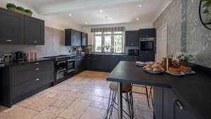 Une cuisine moderne avec des meubles de couleur sombre, un îlot central et une grande fenêtre qui laisse entrer la lumière naturelle.