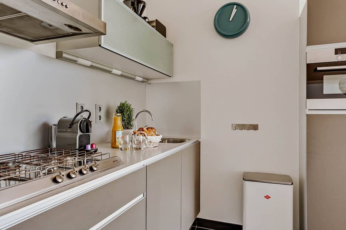 Une cuisine compacte équipée d’une cuisinière à gaz, d’une machine à café et d’un petit réfrigérateur.