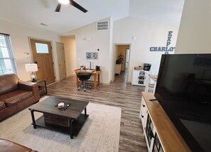 A spacious living room with a brown leather couch, a coffee table, a TV, and a dining area with a wooden table and chairs. - Reid Cottage |3Bd/2Bth Ranch |King Beds |Sleeps 8 (Charlotte)
