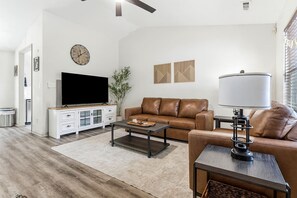 A modern living room with a flat-screen TV, leather sofa, coffee table, and a lamp. - Reid Cottage |3Bd/2Bth Ranch |King Beds |Sleeps 8 (Charlotte)