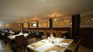 A restaurant with multiple tables set for dining, each with plates, cutlery, and glasses.