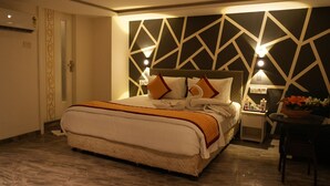 A hotel room with a large bed, a nightstand, a chair, and a decorative wall with geometric patterns. - Citrus Classic Mambakkam Chennai (Tirupporur)