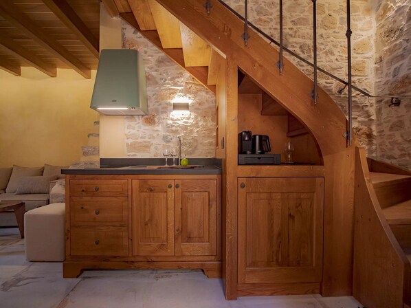 Una cocina con armarios de madera, pared de piedra y escalera de madera.