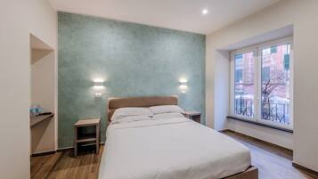 Un dormitorio con cama, mesitas de noche, ventana con vistas y pared con textura.