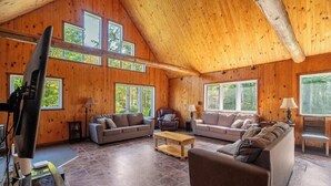 Un salon spacieux aux murs en bois et aux grandes fenêtres, aménagé avec des canapés et une table basse.
